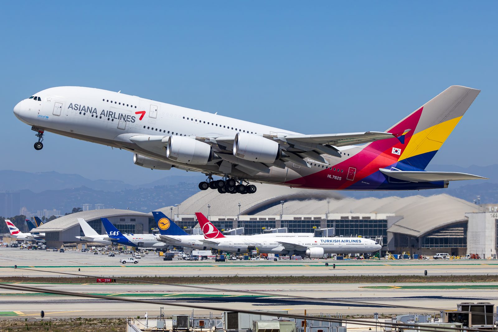 Asiana Airlines Airbus A380 lifting off from Los Angeles International with terminal traffic behind.
