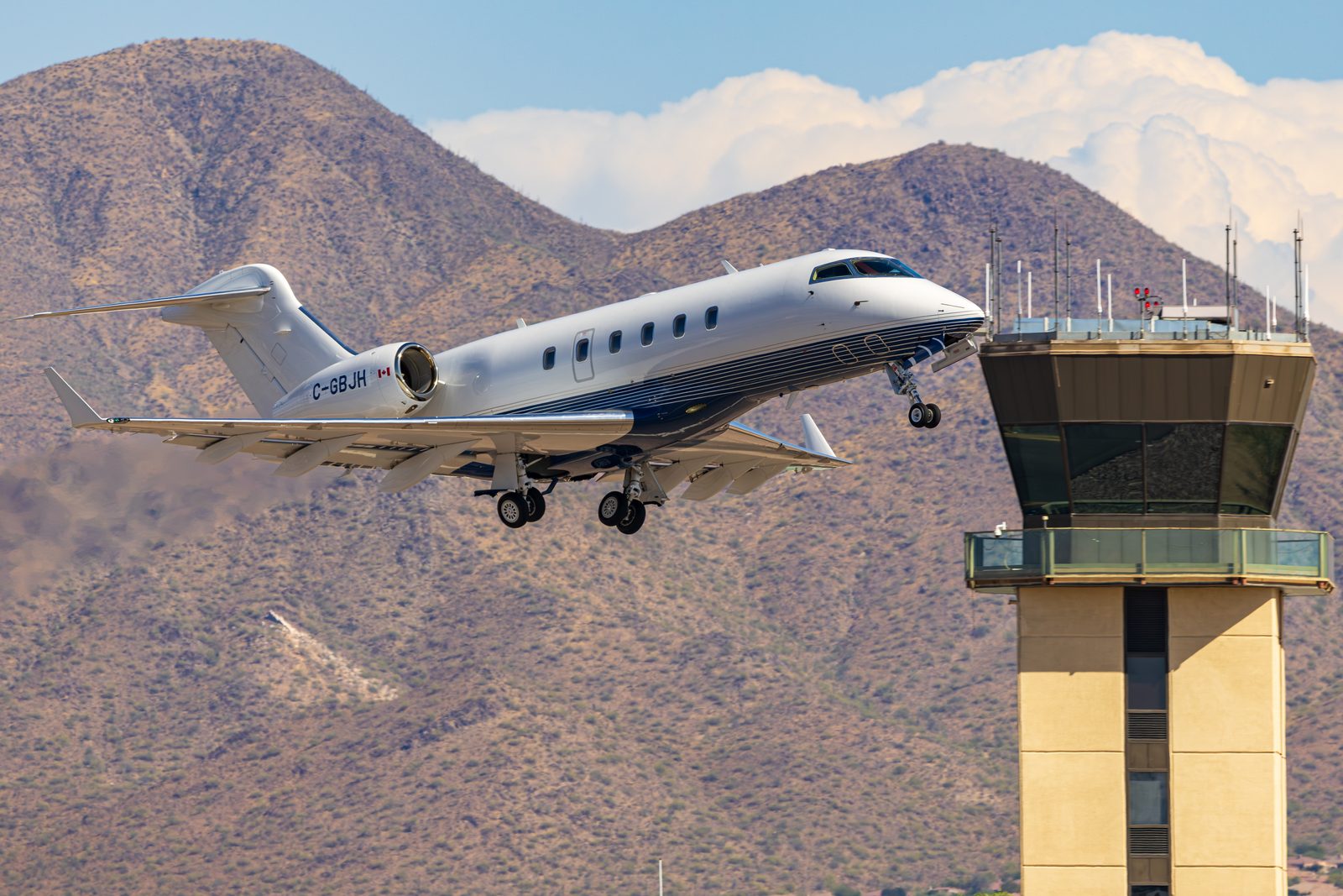 Bombardier Challenger 300 climbing away from Scottsdale with mountains and the control tower behind.