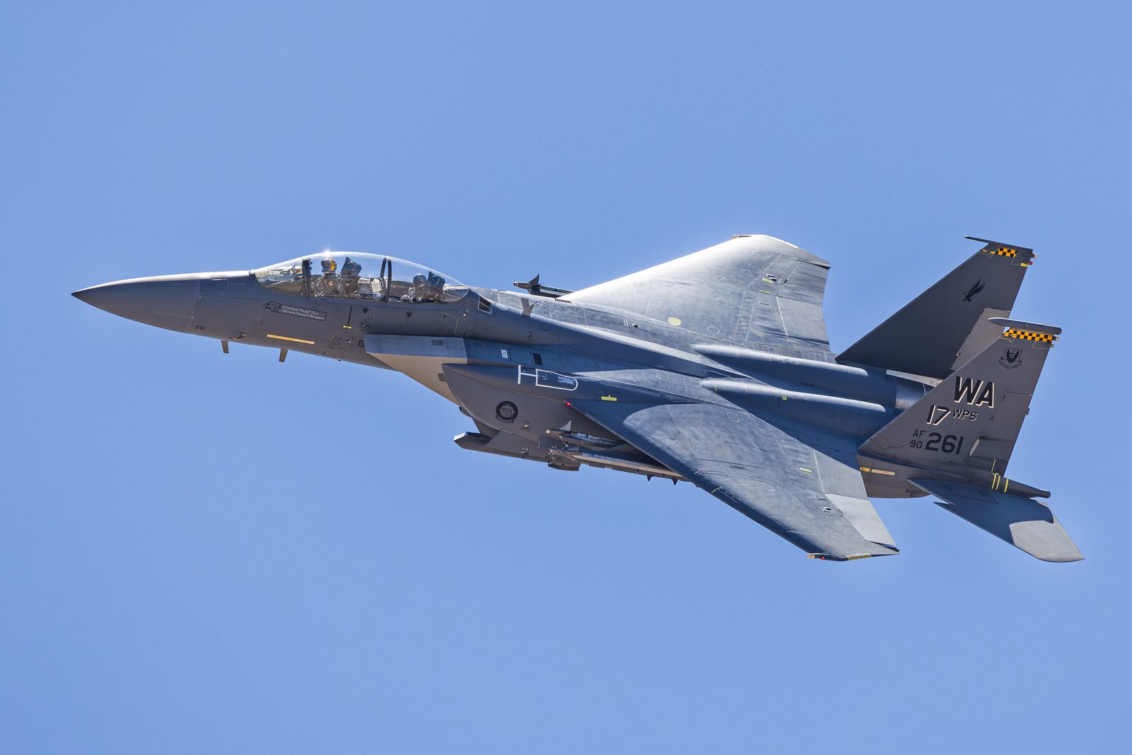 F-15E Strike Eagle climbing steeply after take-off, undersides and pylons visible.