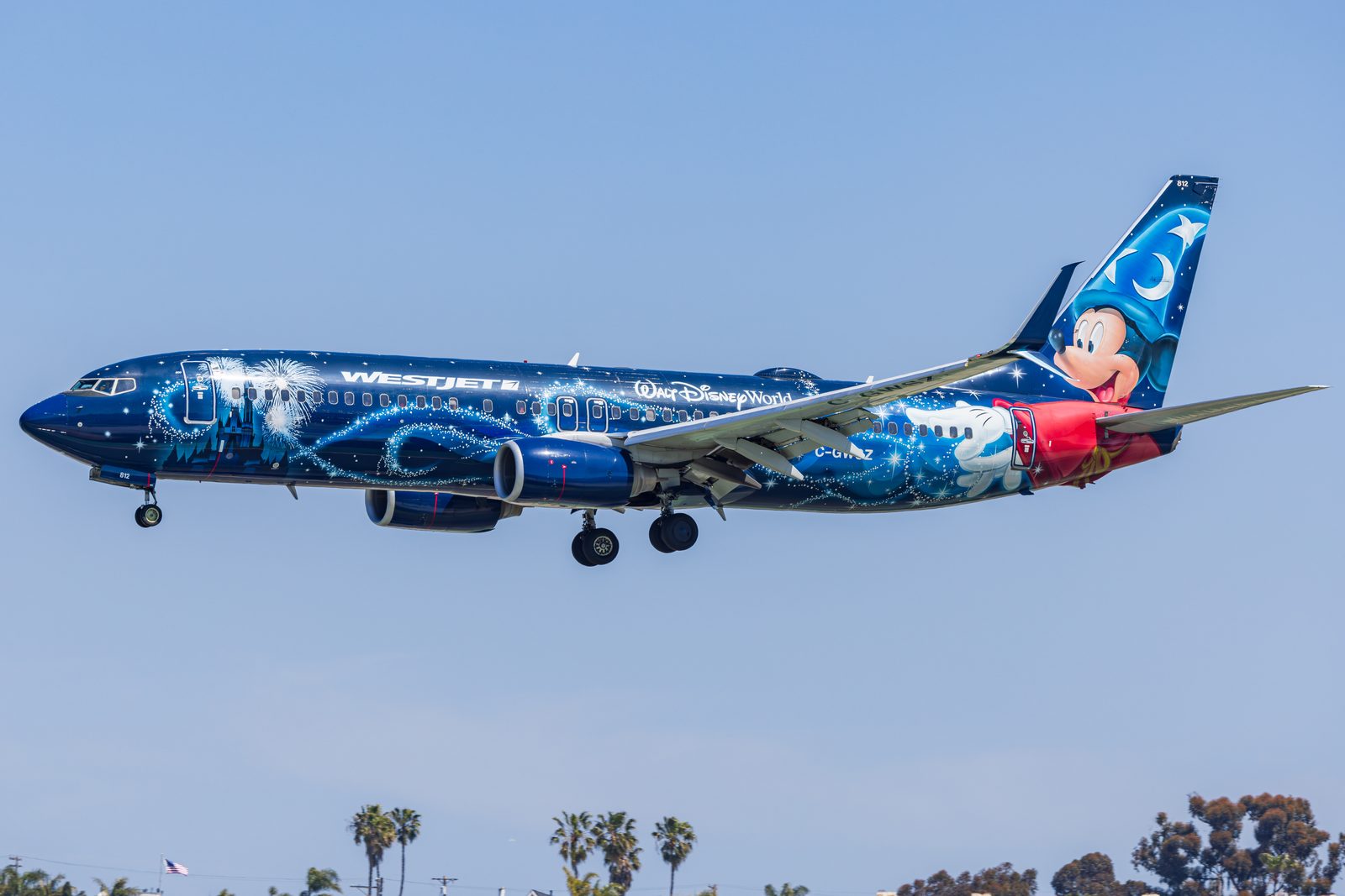 WestJet Boeing 737 in a blue Mickey Mouse livery on final approach to San Diego.